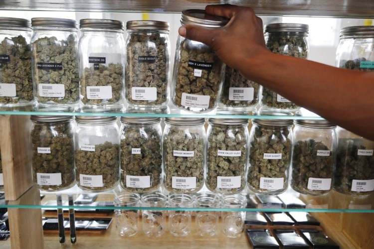 A clerk reaches for a container of marijuana buds for a customer at Utopia Gardens, a medical marijuana dispensary in Detroit.