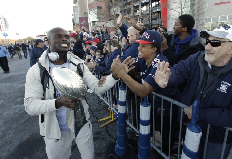 New England cornerback Jason McCourty, left, holds the Lombardi trophy as he greets fans following the team's arrival at Gillette Stadium on Monday.