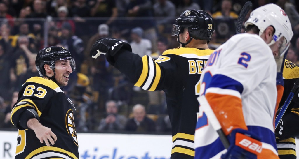 Bruins center Patrice Bergeron, center, is congratulated by teammate Brad Marchand, left, after Bergeron's goal during Boston's 3-1 win over the New York Islanders on Monday in Boston.