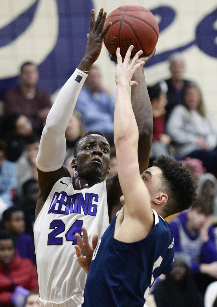 Ben Onek of Deering, left, elevates to get a shot over Jeremiah Alado of Portland during Thursday's game in Portland. Deering won to finish the regular season at 12-6.
