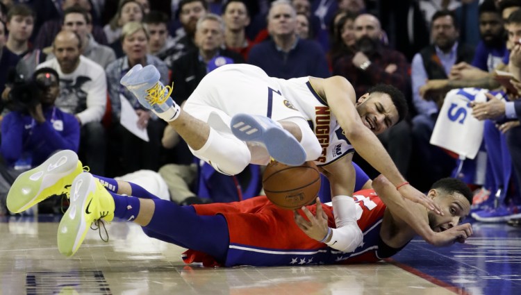 Jamal Murray of the Denver Nuggets, top, and Ben Simmons of the Philadelphia 76ers chase a loose ball Friday night during the first half of Philadelphia's 117-110 victory at home.