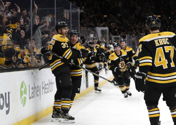 The Bruins stream onto the ice to celebrate after Patrice Bergeron, left, scored the game-winning goal in overtime to give Boston a 5-4 win over the Los Angeles Kind on Saturday in Boston.