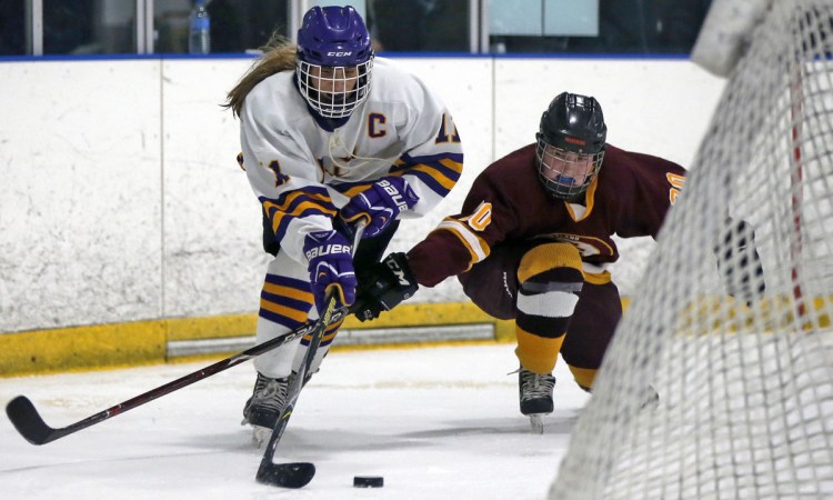 Sophia Pompeo, left, of Cheverus/Kennebunk/Old Orchard Beach tries to skate past Abbey Agrodnia of Cape Elizabeth/Waynflete/South Portland during Saturday's regional semifinal. Sophia's sister, Lucia, scored the game's only goal 1:27 into the second overtime.