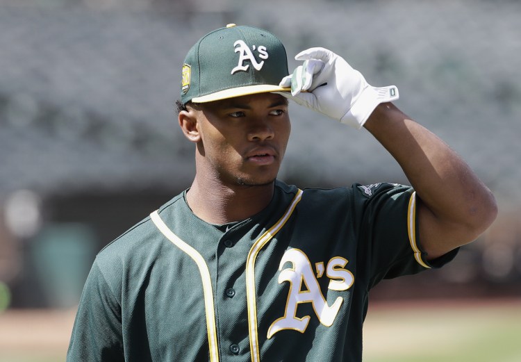 FILE - In this June 15, 2018, file photo, Oakland Athletics draft pick Kyler Murray looks on before a baseball game between the Athletics and the Los Angeles Angels, in Oakland, Calif. The A's still expect Heisman Trophy winner Kyler Murray, the former Oklahoma quarterback and first-round Oakland draft pick, to show up at spring training. He would report right away to big league camp, too. While Murray declared for the NFL draft, A's manager Bob Melvin hopes to manage him in Arizona. (AP Photo/Jeff Chiu, File)