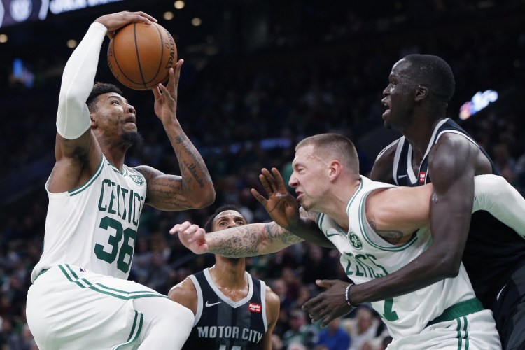Boston Celtics' Marcus Smart, left, goes up to shoot as Daniel Theis, center, screens Detroit Pistons' Thon Maker, right, during the first half of an NBA basketball game in Boston, Wednesday, Feb. 13, 2019. (AP Photo/Michael Dwyer)
