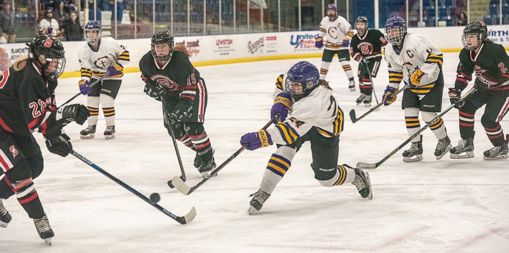 Abby Lamontagne of Cheverus/Kennebunk/Old Orchard Beach takes a shot while defended by Scarborough's Maya Sellinger, left, during the girls' hockey South final Thursday night in Lewiston. Cheverus won in overtime, 3-2.