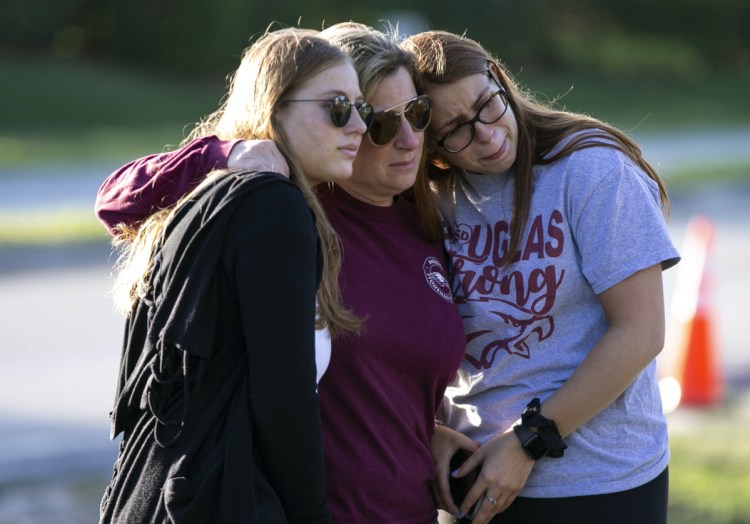 Marjory Stoneman Douglas High student Sophia Rothenberg, right, embraces her mother, Cheryl Rothenberg, and sister Emma Rothenberg at a memorial Thursday marking one year since the mass shooting at the school in Parkland, Florida.