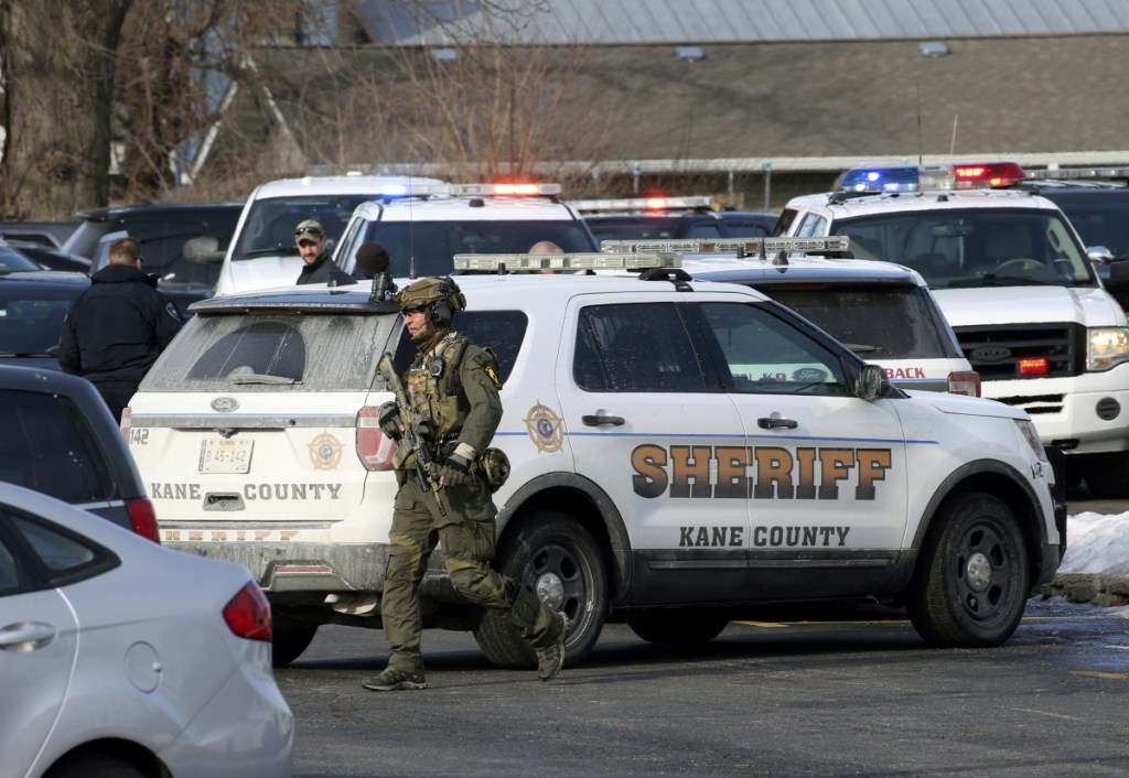 Law enforcement personnel gather near the scene where five people were shot to death in Aurora, Illinois, on Friday.