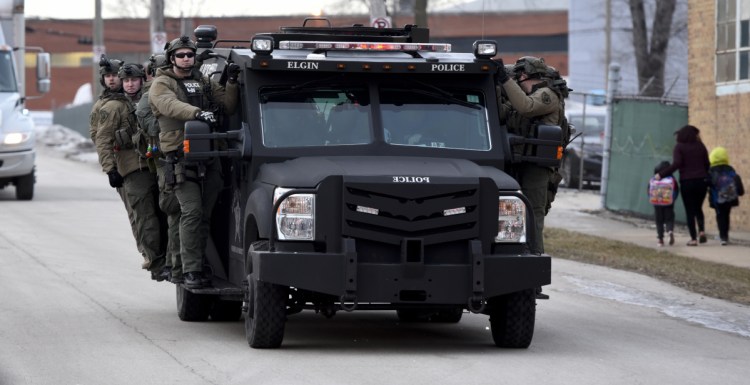 Police officers ride on a vehicle Friday near the site of a shooting at a manufacturing plant in Aurora, Ill.