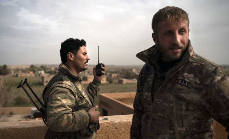 U.S.-backed Syrian Democratic Forces talk on a radio in a rooftop position as the fight against Islamic State militants continues in Baghouz, Syria.