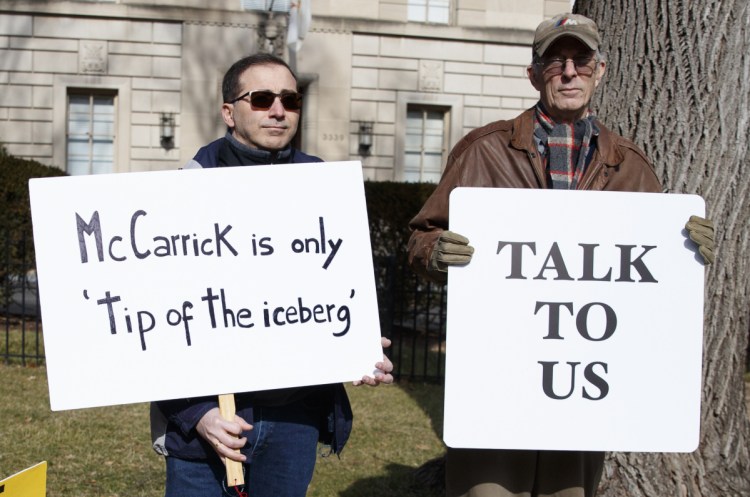 Luis Carvallo, left, and Bob Foss hold signs with a group from Catholic Laity for Orthodox Bishops and Reform outside the Apostolic Nunciature of the Holy See in Washington on Saturday.