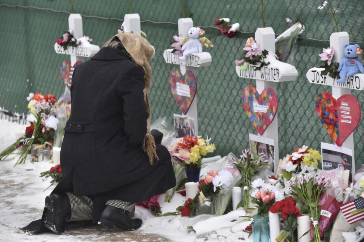 Mourners place flowers at the crosses outside of the Henry Pratt Co. in Aurora, Ill., on Sunday.