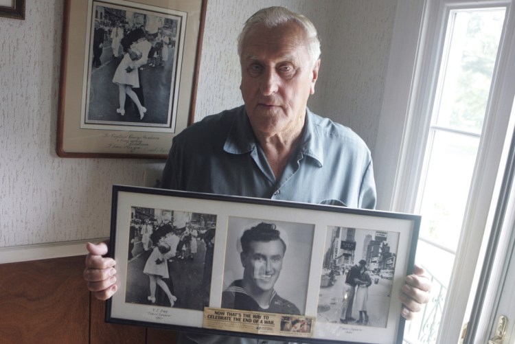 George Mendonsa is shown in 2009 in Middletown, R.I., holding a copy of the famous Alfred Eisenstadt photo of Mendonsa kissing a woman in a nurse's uniform in Times Square on Aug. 14, 1945, while celebrating the end of World War II.