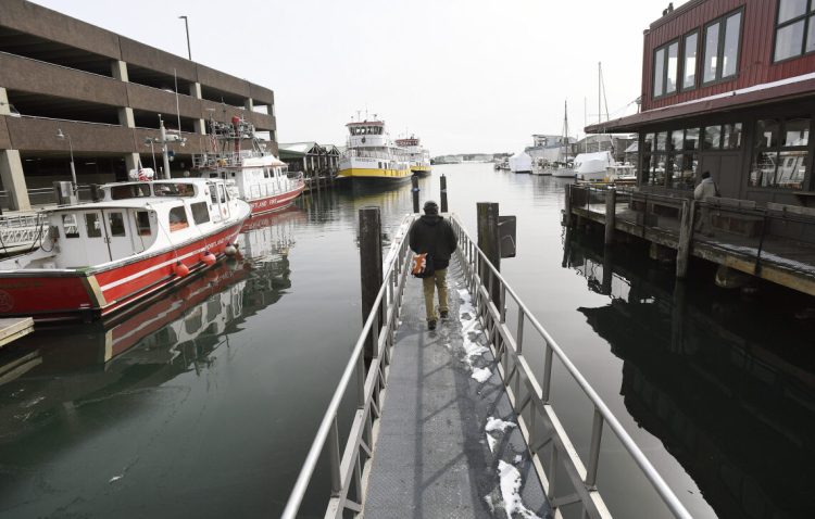 Rick Frantz, with Friends of Casco Bay, walks out on a dock between the Maine State Pier, left and Maine Wharf on Wednesday  to document an abnormally high tide.