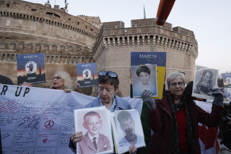 People hold up pictures of those who they say are victims of sexual abuse by priests as they gather during a twilight prayer vigil near Castle Sant' Angelo in Rome on Thursday.
