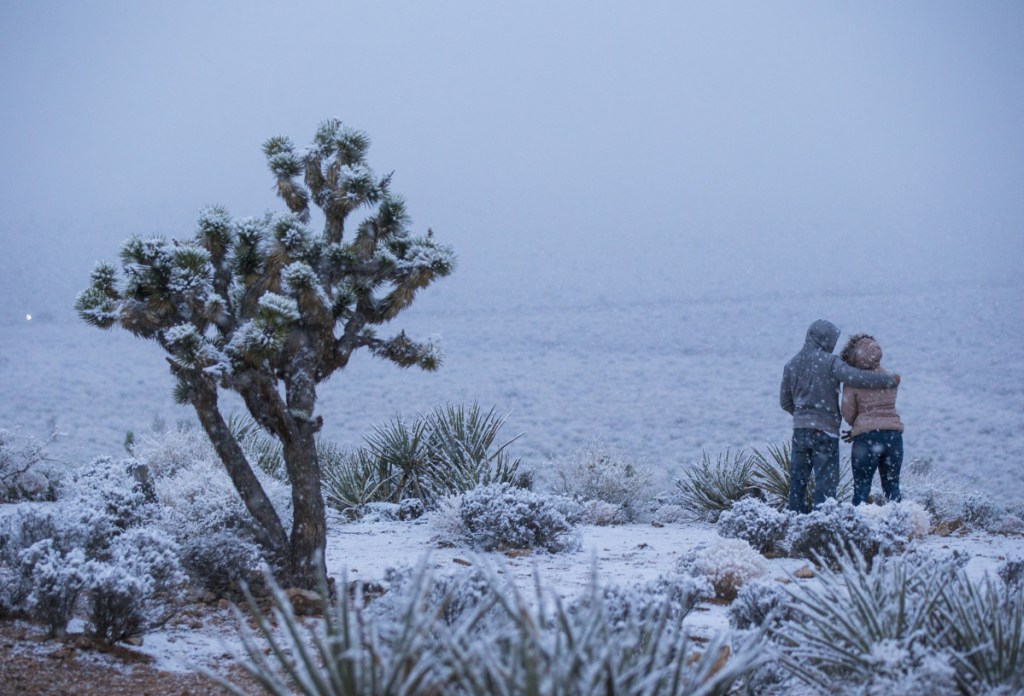 James Minner, of Las Vegas, left, and Candace Reid, of Albuquerque, N.M., watch as snow falls around the overlook at the Red Rock Canyon National Conservation Area outside of Las Vegas on Wednesday, Feb. 20, 2019. (Chase Stevens/Las Vegas Review-Journal via AP)