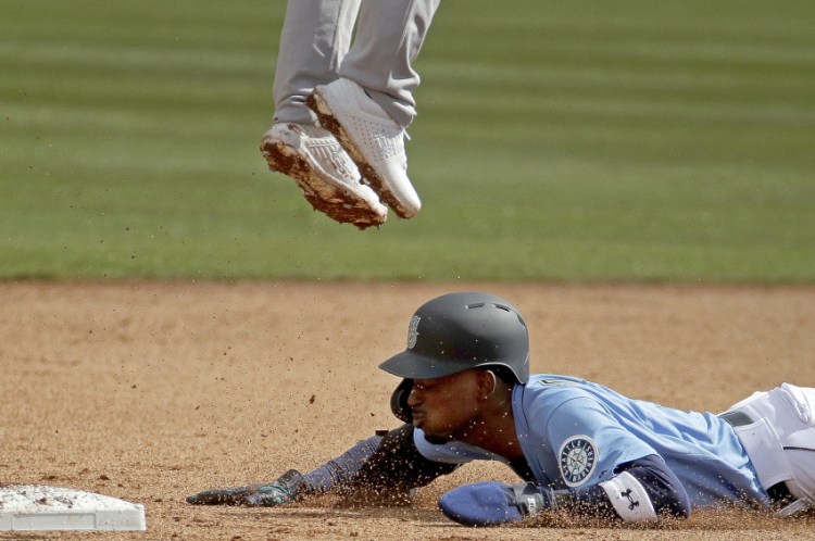 Dee Gordon of Seattle slides under – well under – Oakland second baseman Franklin Barreto to steal a base during Seattle's 8-1 victory.