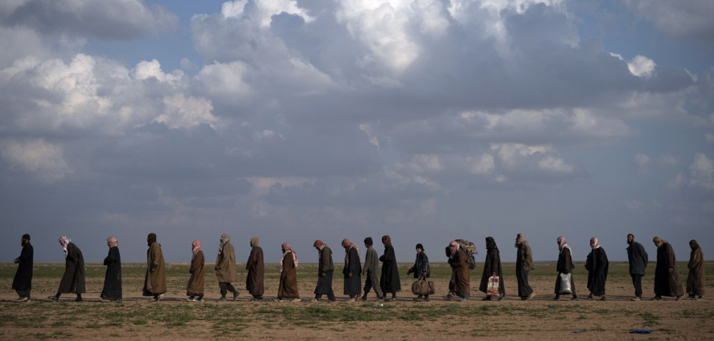 Men head for a screening site after being evacuated from Baghouz, eastern Syria, on Friday.