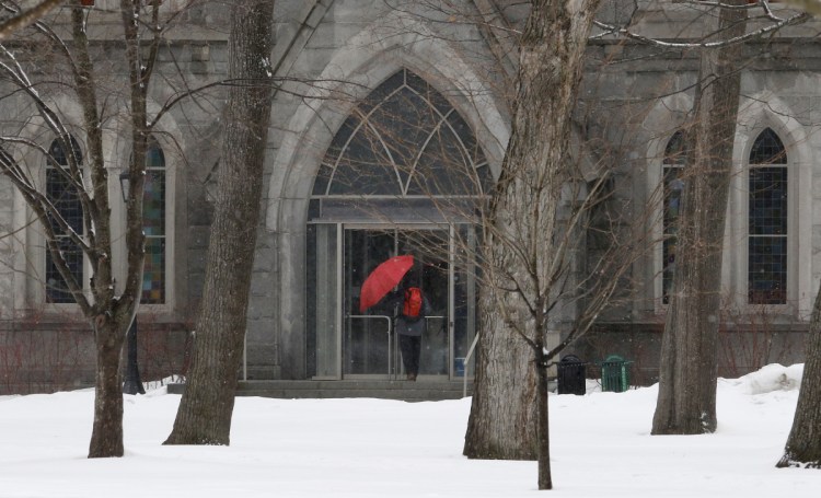 A unidentified student escapes the snow and rain as he ducks into Memorial Hall at Bowdoin College in Brunswick on Sunday. On Monday, Maine will see high winds followed by dropping temperatures.