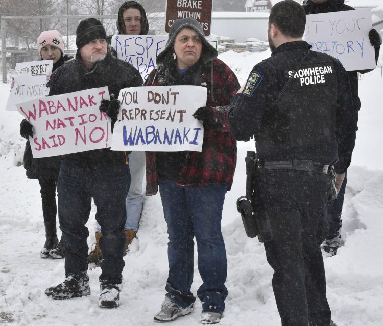 Skowhegan police Officer Jake Boudreau asks members of the Wabanaki nation, including Diana Owen, of Milo, to stay out of the public roadway Sunday while they protest a nearby discussion in Skowhegan between the Native American Guardians Association and a group of local residents who support the continued use of the term "Indian" in connection with local school sports teams.