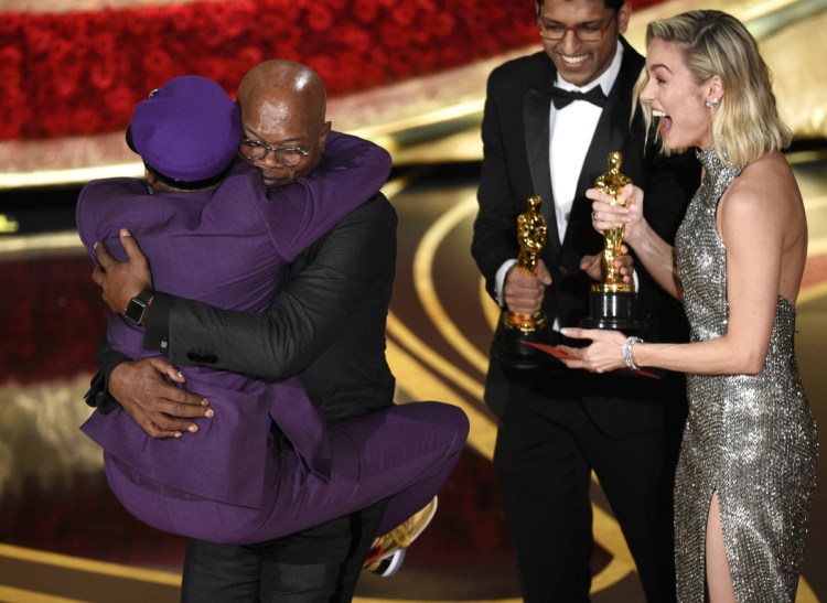 Samuel L. Jackson, center left, embraces Spike Lee, winner of the award for best adapted screenplay for "BlacKkKlansman" as Brie Larson, right, looks on, at the Oscars.