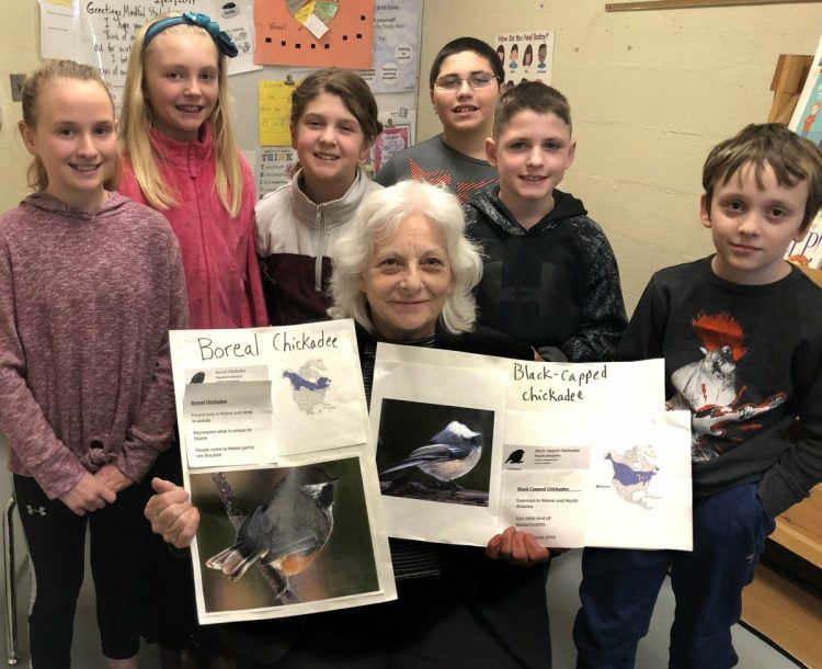 Surrounded by Margaret Chase Smith fourth-grade students, state Rep. Betty Austin of Skowhegan holds a picture of a boreal chickadee, on left, and a black-capped chickadee that may be chosen to be the officially designated Maine state bird after Austin submits the bill to a committee in Augusta this week. Students wrote letters that will accompany Austin.