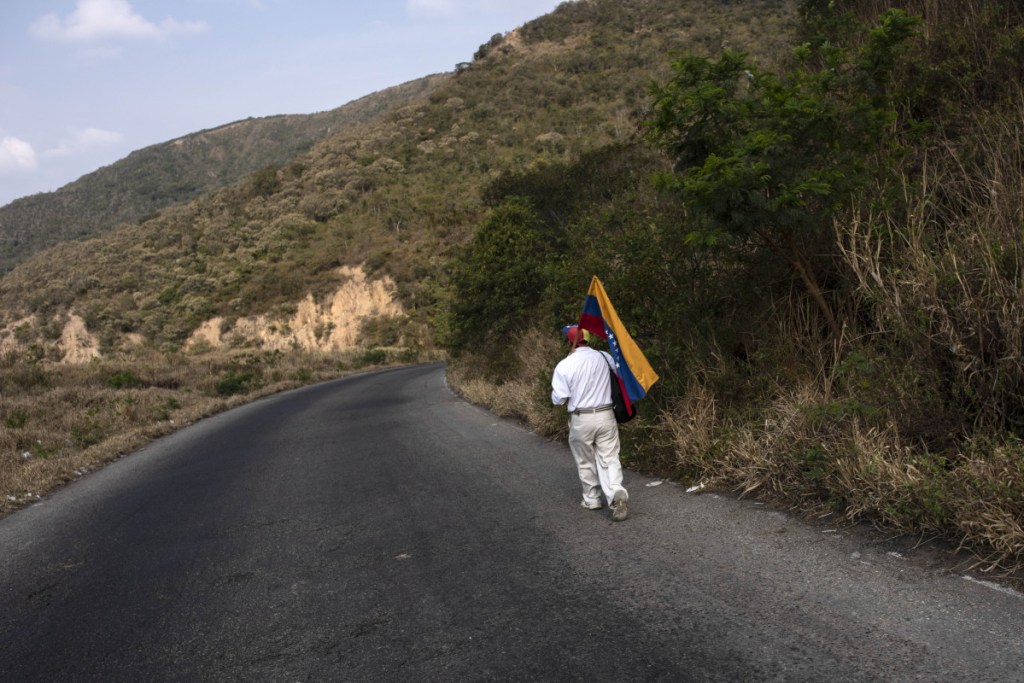 An opposition supporter walks down a highway that leads to the Colombian border outside of Capacho, Venezuela, on Saturday.