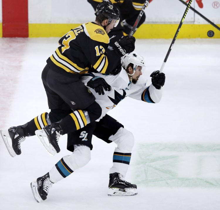 Charlie Coyle, playing his first home game for Boston, leaps onto the back of San Jose defenseman Erik Karlsson as they chase a puck in the first period Tuesday night. The Bruins won 4-1.