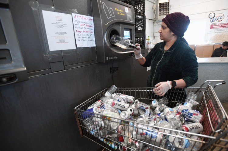 Pooja Paten, an employee of Madden Beverage and Redemption Center in Saco, loads returnables into a reverse vending machine at the redemption center Wednesday.