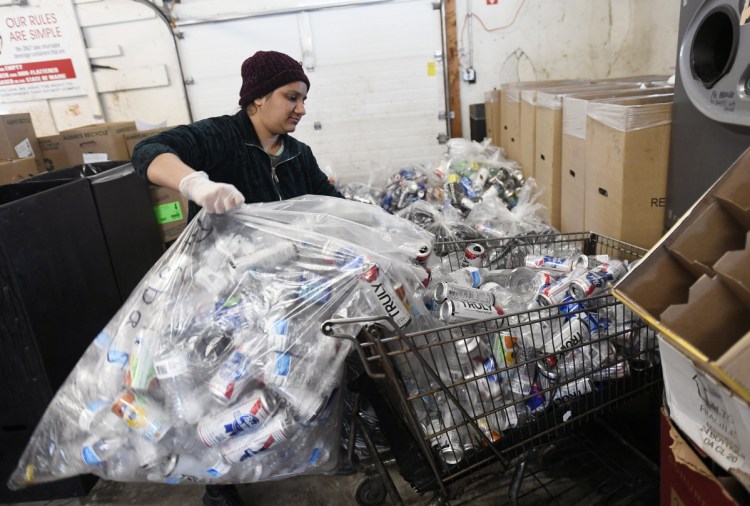 Pooja Paten, an employee of Madden Beverage and Redemption Center in Saco, empties a bag of returnables into a shopping cart to load into a reverse vending machine Wednesday.
