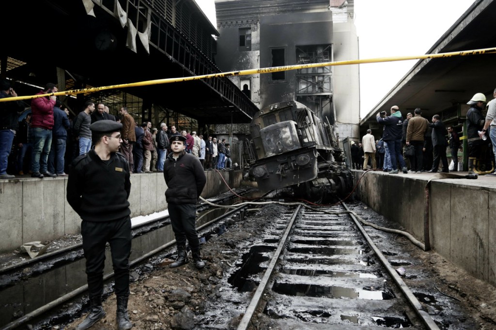Police stand guard in front of a damaged train inside Ramsis train station in Cairo on Wednesday.