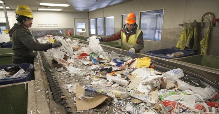 Hector Reinos, left, and Arturo Santos pull out plastics from a conveyor of paper to be recycled at ecomaine in Portland. Plastic is of limited utility on the recycling market.