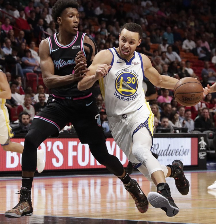 Warriors guard Stephen Curry dribbles toward the basket against Heat guard Josh Richardson in the first half Wednesday night at Miami.