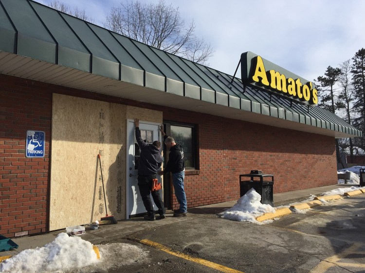 Mike Frongillo, left, and Aaron Bourassa of Great Falls Construction finish installing a temporary doorway Saturday after a customer crashed into the glass entryway of Amato's at 1108 Broadway in South Portland. The morning crash closed the pizza-and-sandwich shop for the day, but it will be open as usual Sunday from 7 a.m. to 11 p.m.