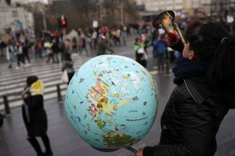 A woman holds a globe as she plays a trumpet during a climate change protest in Brussels last month. Thousands of teenagers in Belgium have skipped school for the fourth week in a row in an attempt to push authorities into providing better protection for the world's climate.