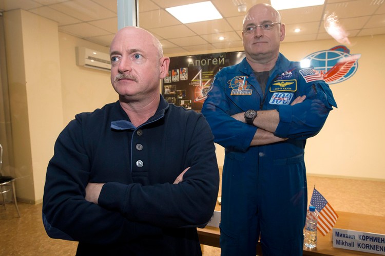 Scott Kelly, right, crew member of the mission to the International Space Station, stands behind glass in a quarantine room, behind his brother, Mark Kelly, also an astronaut in 2015.