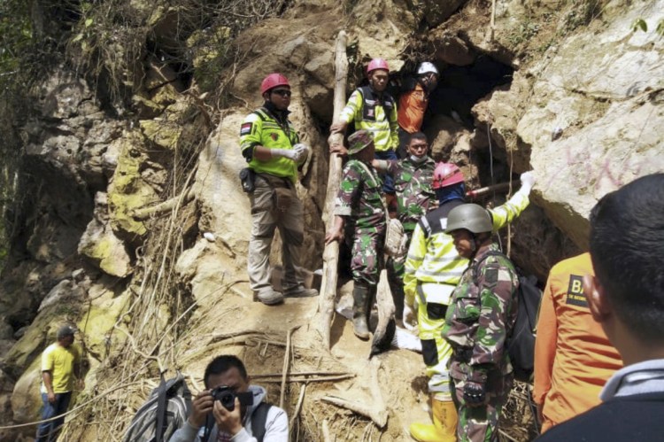 Rescuers stand at the entrance of a collapsed mine in Bolaang Mongondow, North Sulawesi, Indonesia, on Thursdayi. They say "signs of life have faded away" but are still continuing rescue efforts.