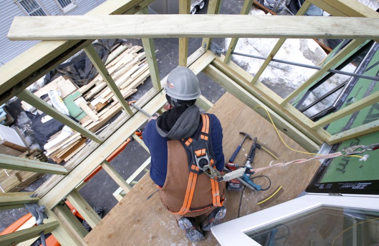 Carpenter Jay Nilsson lays decking on a balcony at Parris Terrace, a mid-range condominium project under construction in Portland's Bayside. Construction costs have risen to their highest point since the Great Recession.