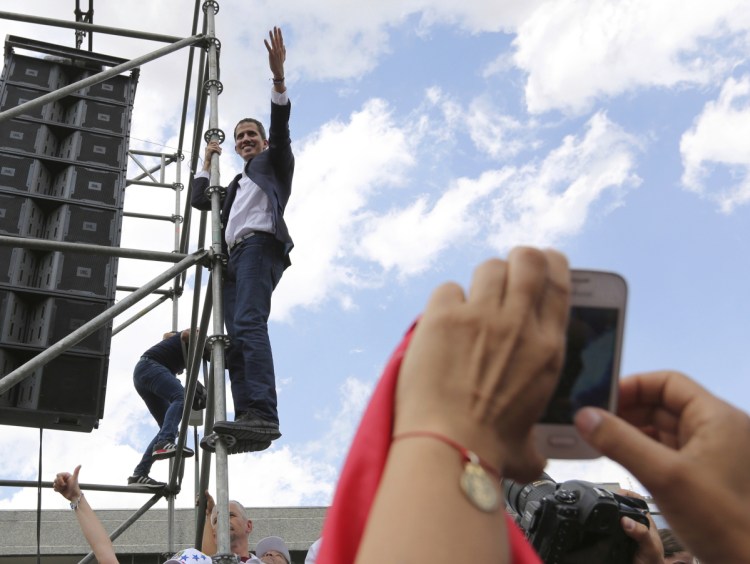 Venezuelan Congress President Juan Guaido, an opposition leader who declared himself interim president, waves from the scaffolding after speaking at a rally demanding the resignation of Venezuelan President Nicolas Maduro in Caracas, Venezuela, on Monday. The United States and about 50 other countries recognize Guaido as the rightful president of Venezuela, while Maduro says he is the target of a U.S.-backed coup plot.