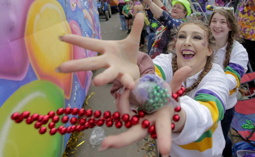 A Mardi Gras celebrant catches a bauble tossed from a float along the Uptown route in New Orleans on Sunday.