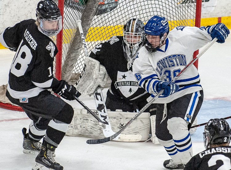 St. Dominic Academy goalie Miloslav Gaston Fuksa eyes the puck as it is tipped by Lewiston's Tyler Marcoux during Tuesday night's playoff game at the Androscoggin Bank Colisee in Lewiston.