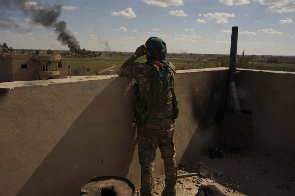 A U.S.-backed Syrian Democratic Forces fighter watches as smoke billows from an area still held by Islamic State militants in Baghouz, Syria, on Sunday.
