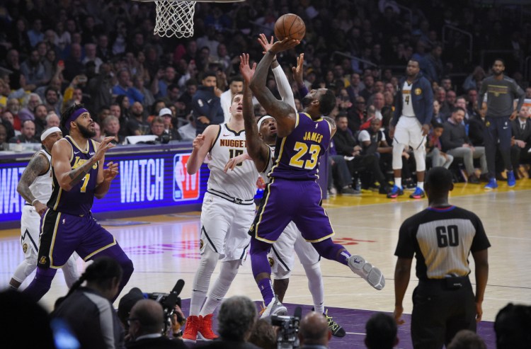 Los Angeles Lakers forward LeBron James (23) shoots and scores as Denver Nuggets forward Torrey Craig, second from right, defends and center Nikola Jokic, center, watches along with Lakers center JaVale McGee, left, during the first half of an NBA basketball game Wednesday, March 6, 2019, in Los Angeles. With that basket, James moved past Michael Jordan for fourth place on the NBA career scoring list. (AP Photo/Mark J. Terrill)