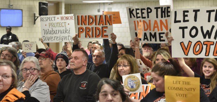 People for and against using the "Indians" nickname and mascot in SAD 54 schools show signs to school board members during the meeting Thursday night in Skowhegan.