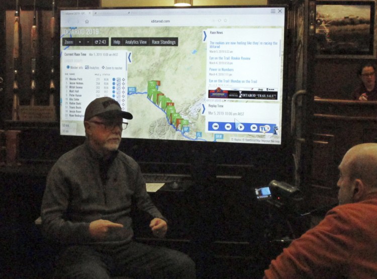 Iditarod spokesman Chas St. George sits in front of a large screen set up inside a hotel in Anchorage on Tuesday for public updates in the 1,000-mile Iditarod Trail Sled Dog Race. 