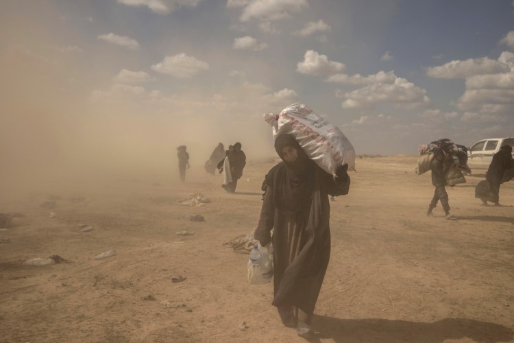 A woman carries supplies from a reception area for people evacuated from the last shred of territory held by Islamic State militants, outside Baghouz, Syria, on Wednesday.