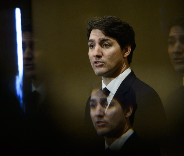 Canadian Prime Minister Justin Trudeau is seen through a beveled pane of glass in a door at a conference Friday.