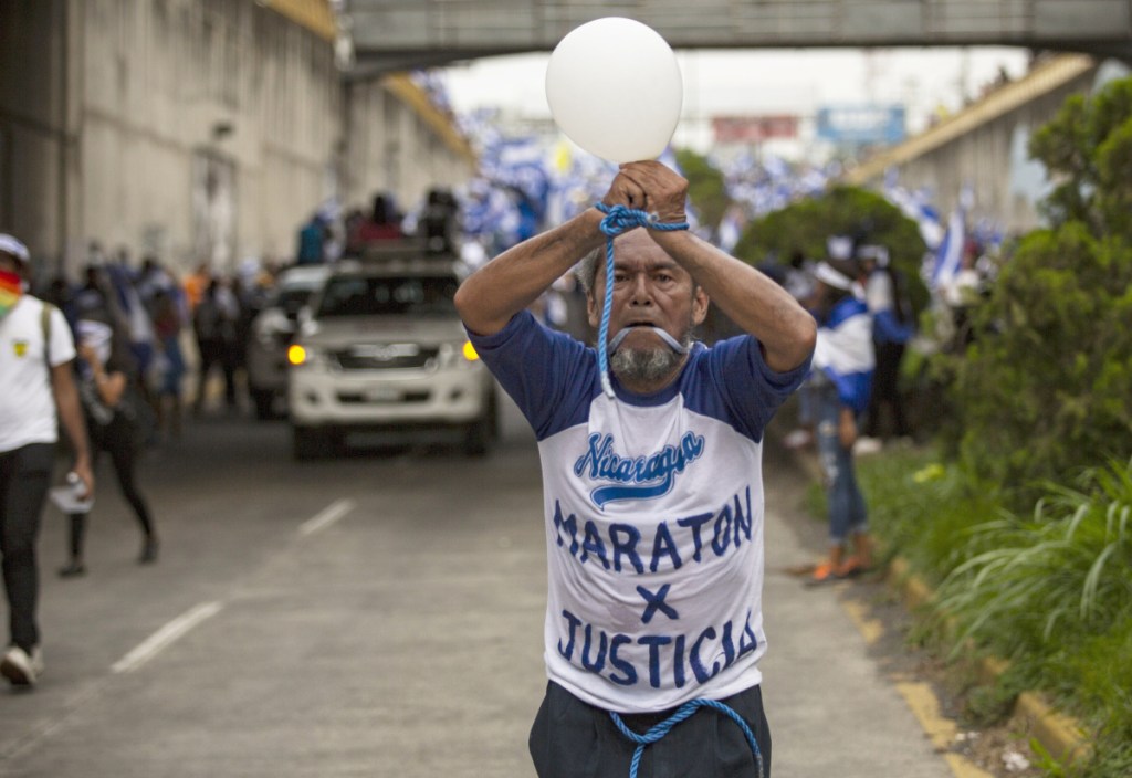 Alex Vanegas runs with his hands tied and his mouth gagged during a protest march against the government of President Daniel Ortega in Managua, Nicaragua, last July. During the unrest that rocked Nicaragua last year, Vanegas became a prominent symbol of opposition to Ortega, instantly recognizable for his salt-and-pepper beard and shirts emblazoned with anti-government slogans as he jogged through the streets of Managua in the blue and white of his country's flag.
