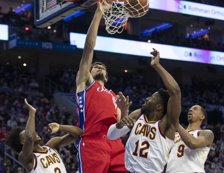 Philadelphia's Boban Marjanovic goes up for a dunk over three Cleveland players during the 76ers' win Tuesday.