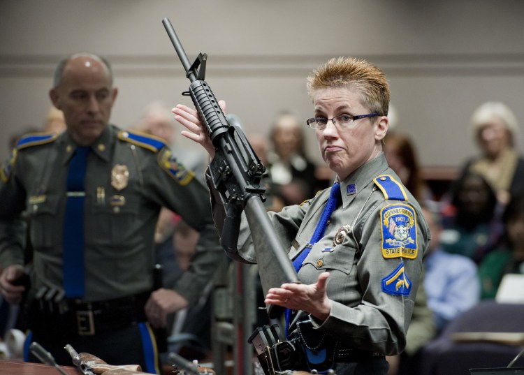 Detective Barbara J. Mattson of the Connecticut State Police holds a Bushmaster AR-15 rifle during a 2013 hearing in Hartford, Conn. A divided Connecticut Supreme Court ruled Thursday that gun maker Remington can be sued over how it marketed the Bushmaster rifle, whch was used in the massacre.